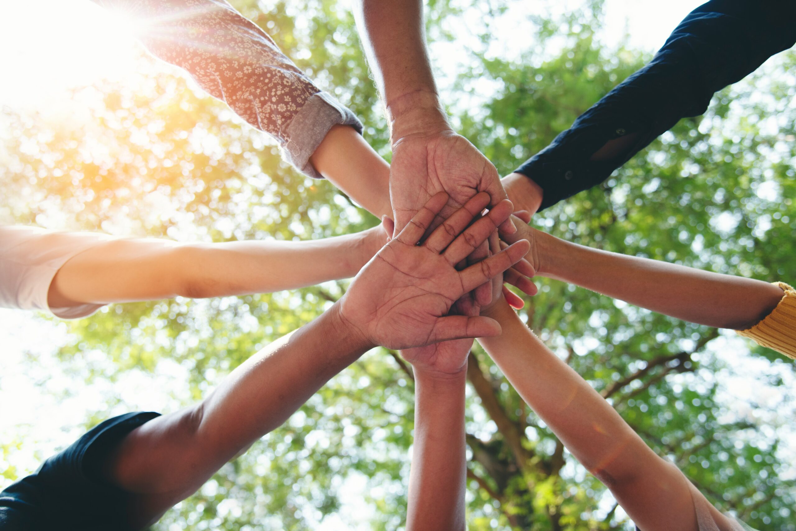 Group of hands joined together in a circle, symbolising shared ownership under employee share ownership plans in Kenya