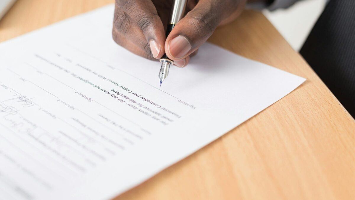 African businessman signing documents, illustrating ARIPO vs OAPI regional IP filing systems