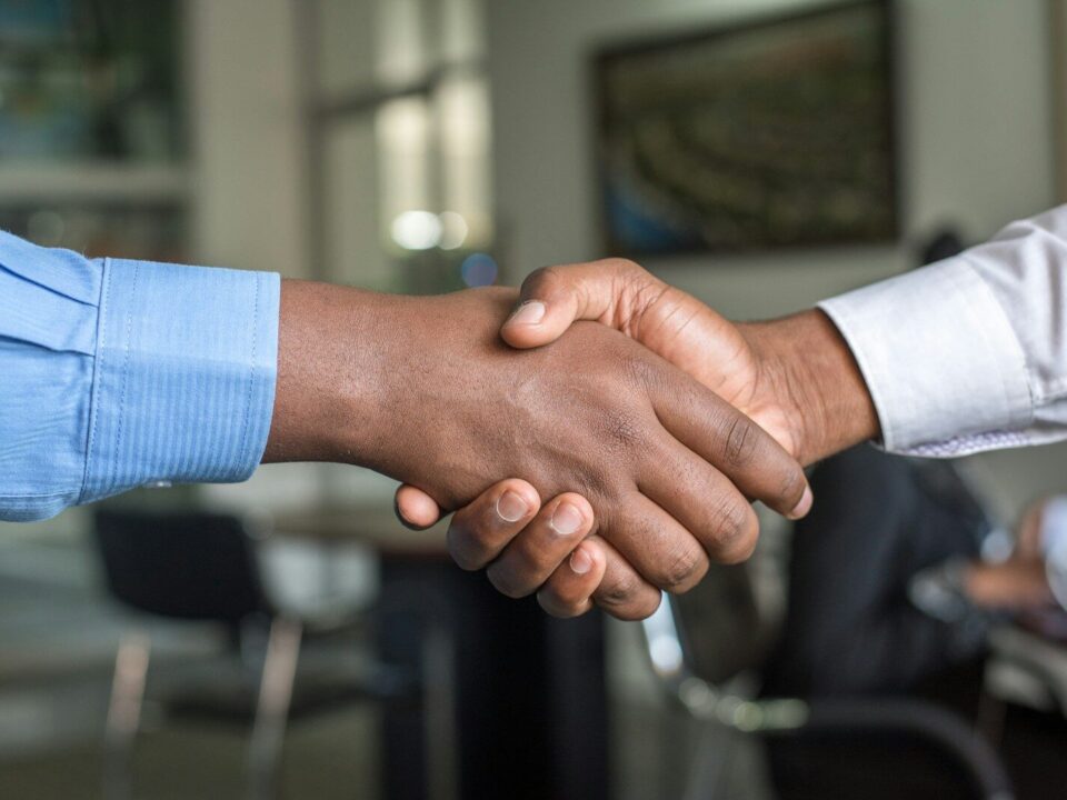 African business professionals shaking hands after a related party transaction agreement