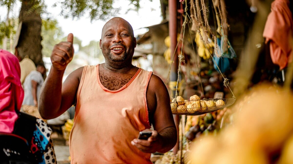 African market vendor at a fruit stand, representing goods the Anti-Counterfeit Authority Kenya relies on works to protect