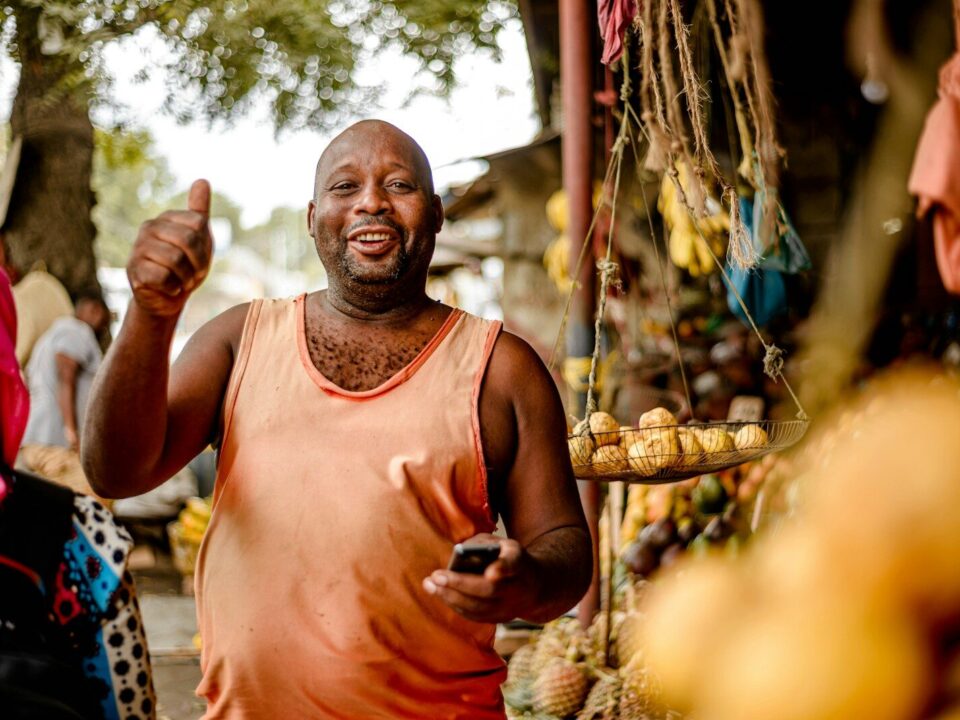 African market vendor at a fruit stand, representing goods the Anti-Counterfeit Authority Kenya relies on works to protect