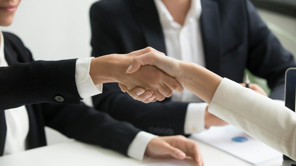 Two business people shaking hands, representing a cross-border M&A or investment transaction involving a Kenyan target’s IP portfolio