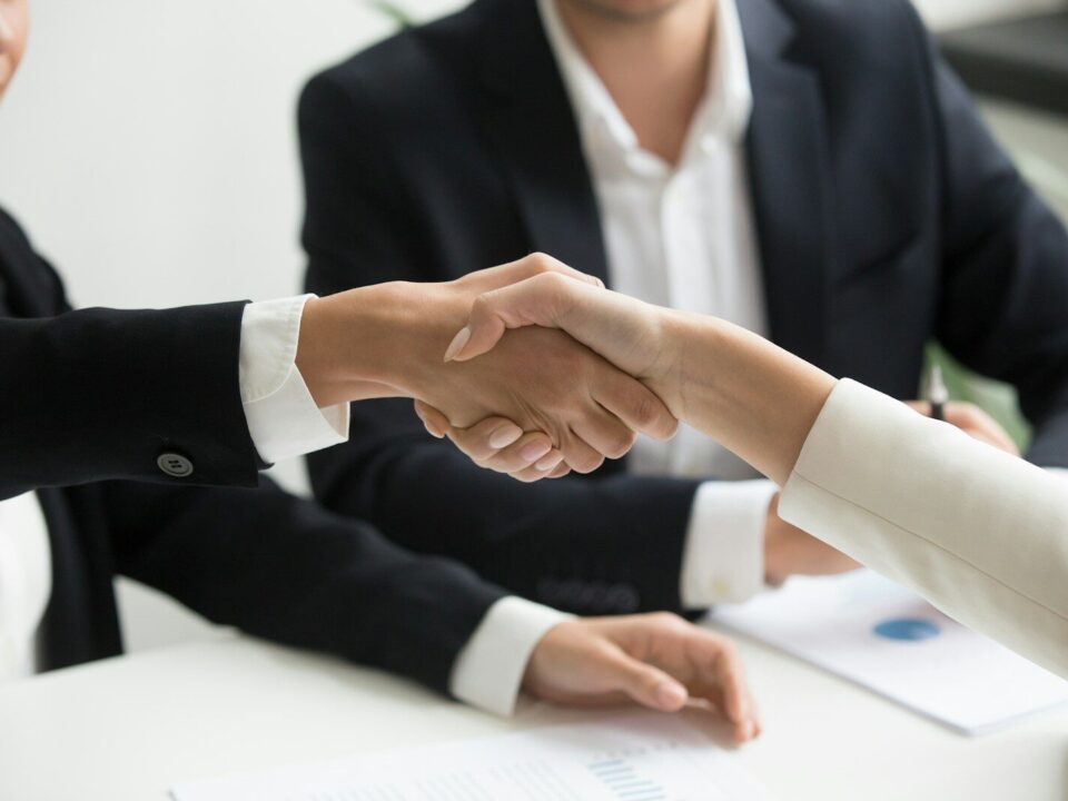 Two business people shaking hands, representing a cross-border M&A or investment transaction involving a Kenyan target’s IP portfolio