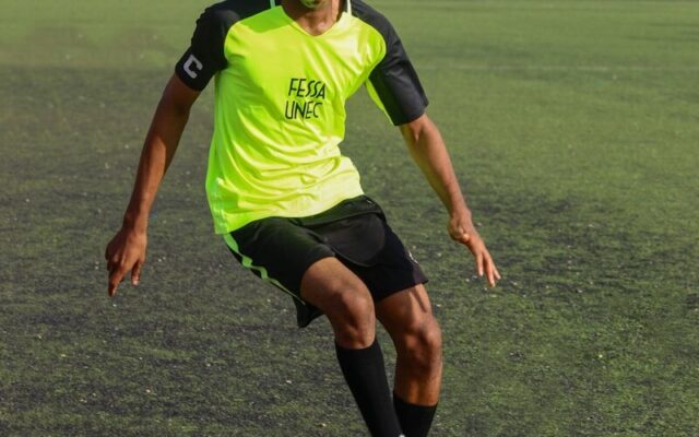 A young African footballer controlling the ball on a training pitch