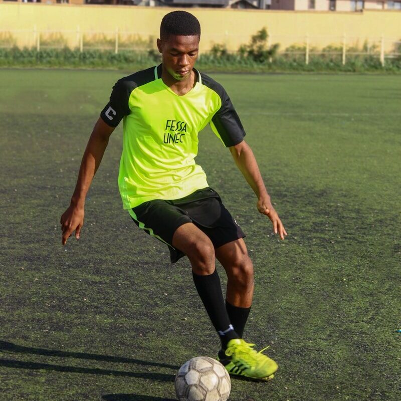 A young African footballer controlling the ball on a training pitch