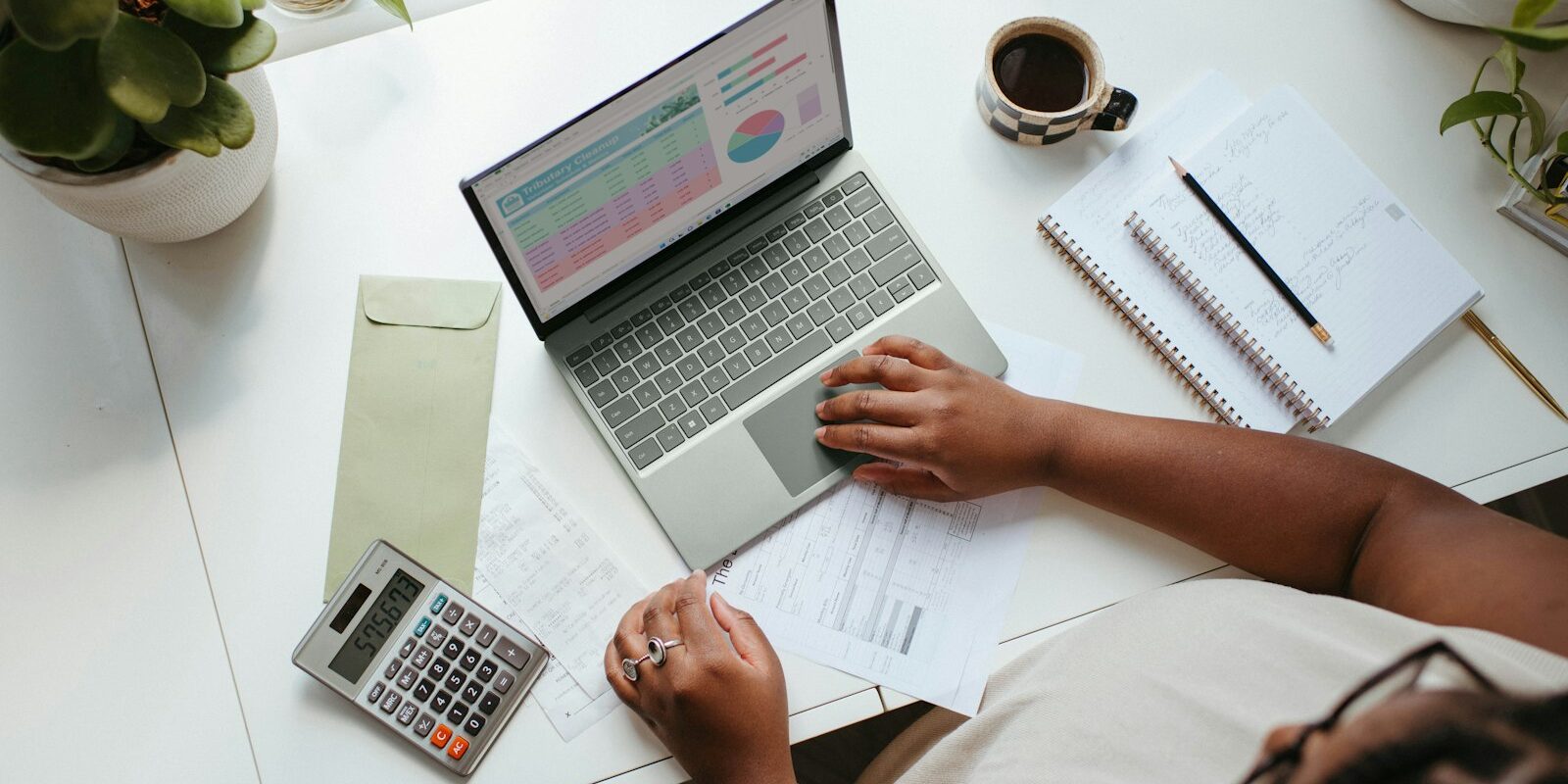 VASP statutory management: an African finance professional reviewing accounts on a laptop with a calculator and notebook