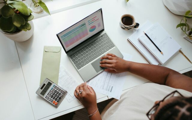 VASP statutory management: an African finance professional reviewing accounts on a laptop with a calculator and notebook