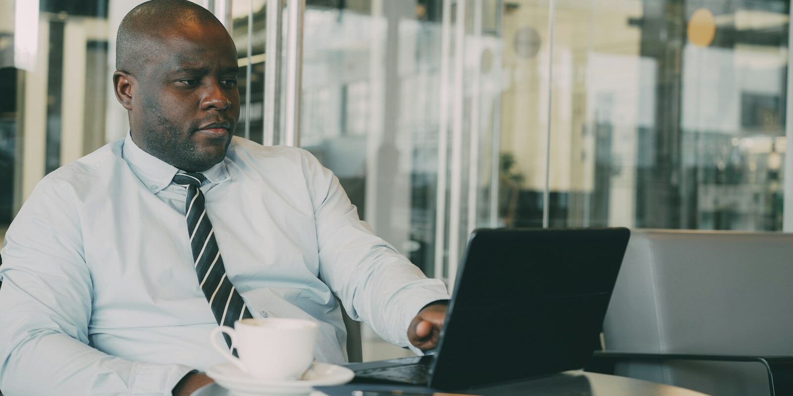 Legal Notice 172: an African compliance officer reviewing sanctions screening on a laptop in a glass-walled office