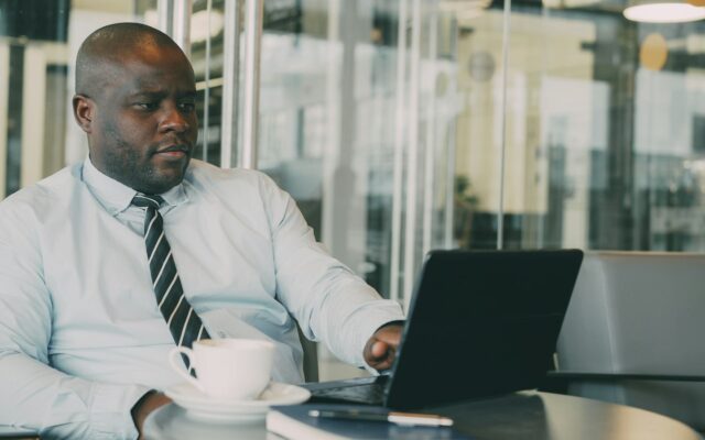 Legal Notice 172: an African compliance officer reviewing sanctions screening on a laptop in a glass-walled office