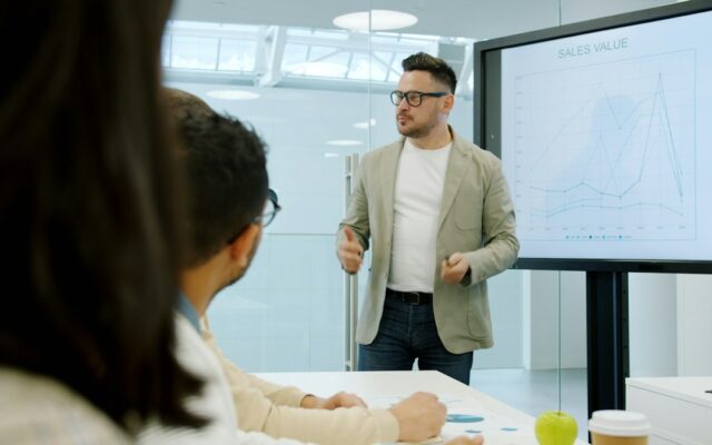 A presenter showing data charts on a screen to board members