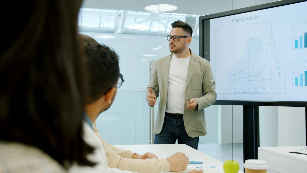 A presenter showing data charts on a screen to board members