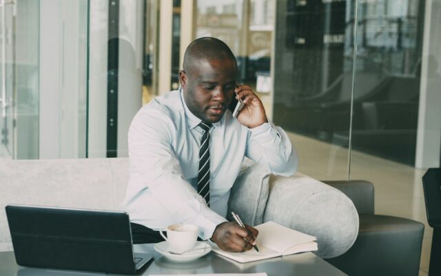 A businessman on the phone taking notes at his desk