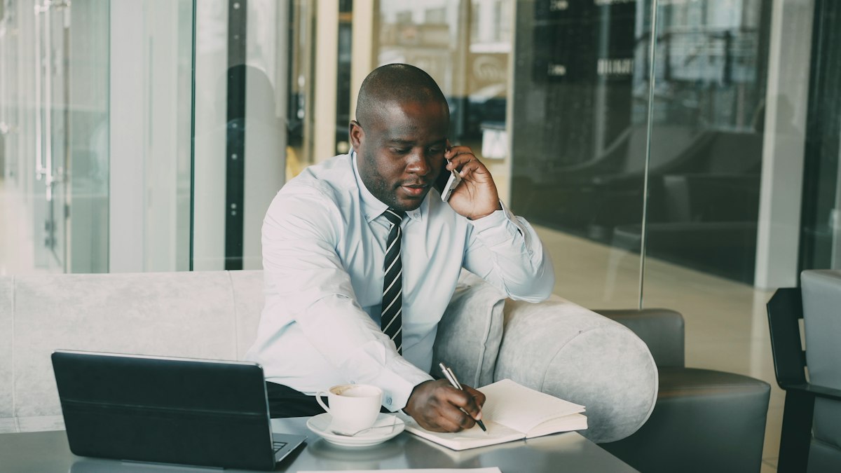 A businessman on the phone taking notes at his desk