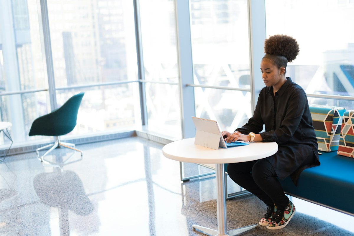 A businesswoman working on a laptop at a small table
