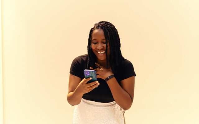 African woman smiling while using a mobile lending app on her smartphone