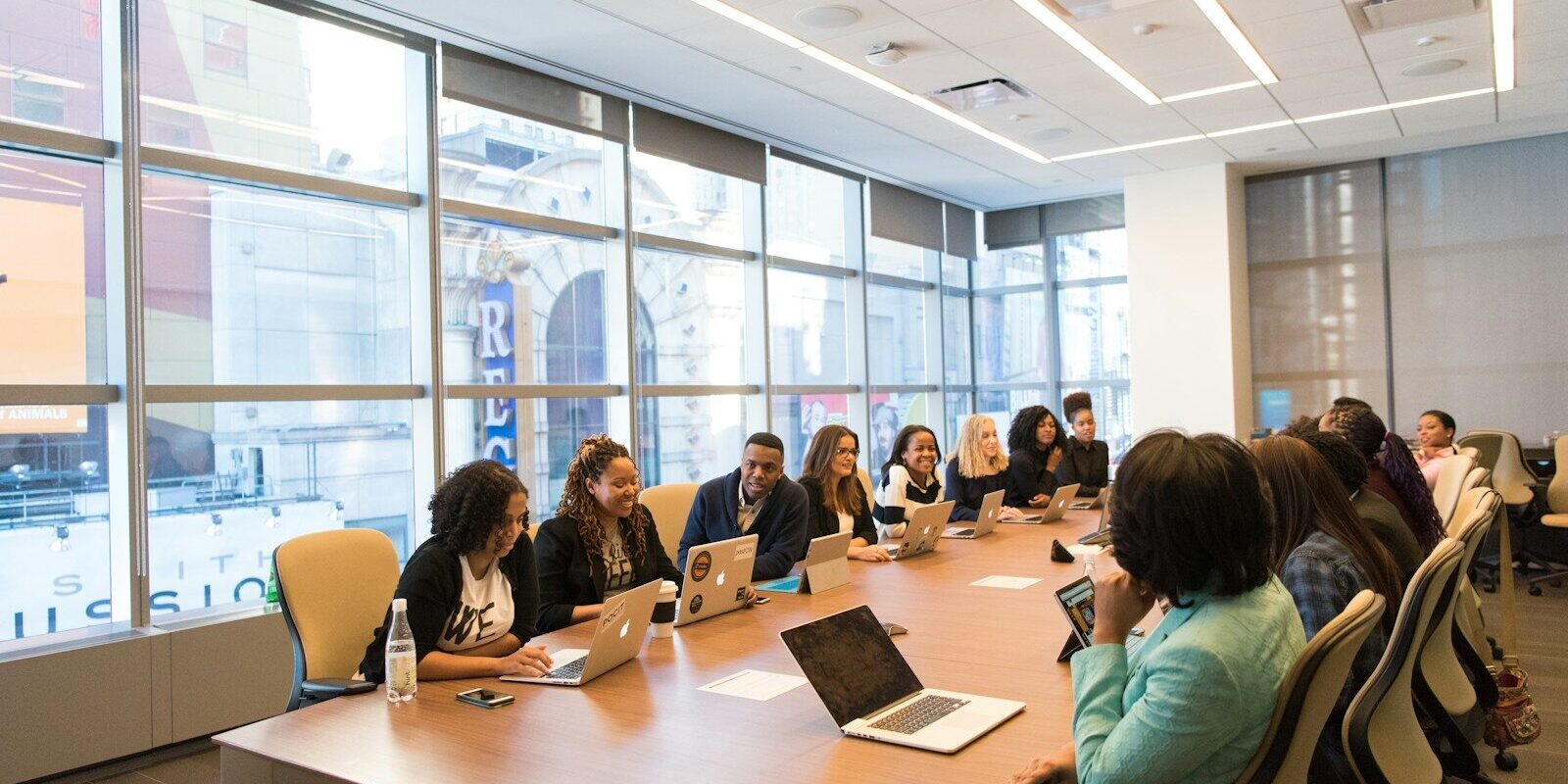 Diverse team of African business professionals in a boardroom meeting on laptops, representing a corporate group discussing an internal reorganisation.