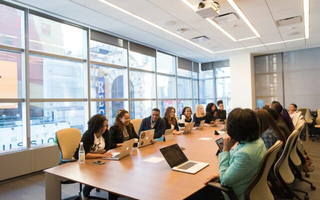 Diverse team of African business professionals in a boardroom meeting on laptops, representing a corporate group discussing an internal reorganisation.