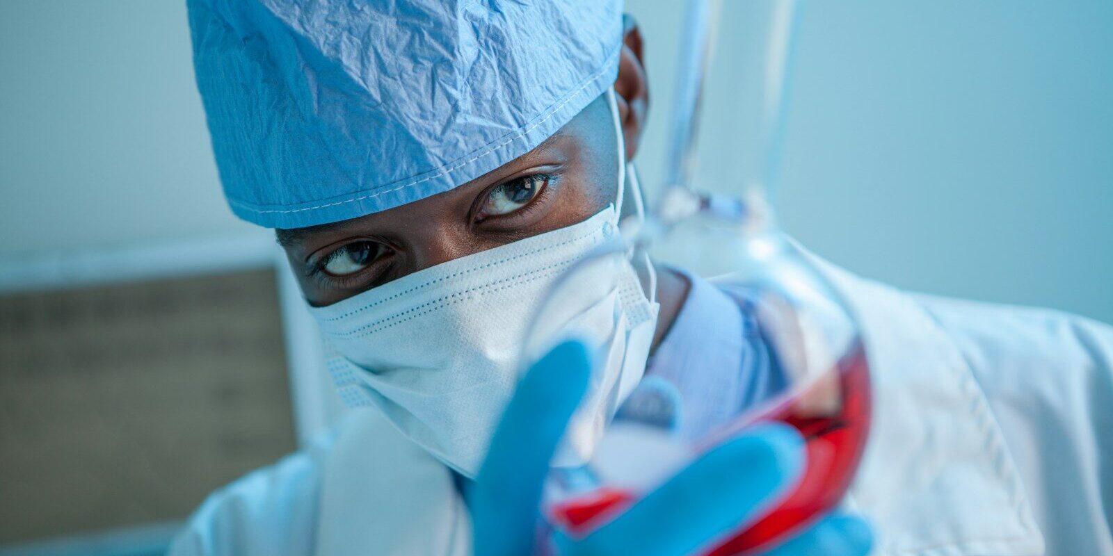 African pharmaceutical researcher holding a laboratory flask of locally manufactured product
