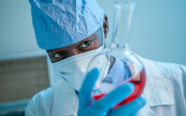 African pharmaceutical researcher holding a laboratory flask of locally manufactured product