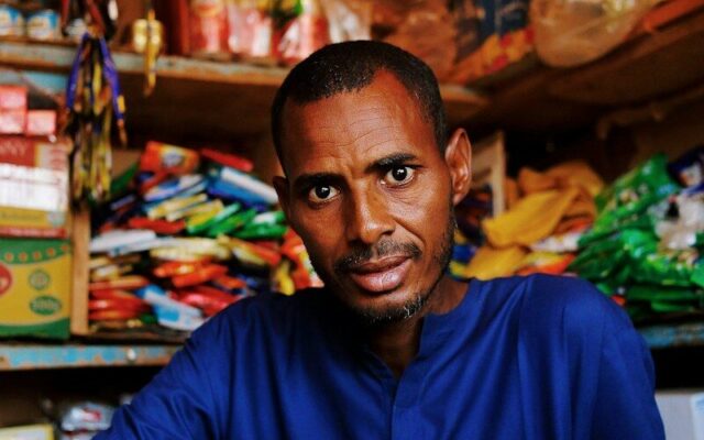 Kenyan shopkeeper surrounded by stocked inventory shelves, representing movable assets that can secure business credit
