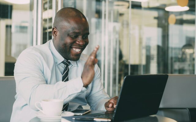 African business professional on a video call with his laptop in a modern office, representing non-resident digital businesses engaging Kenyan users
