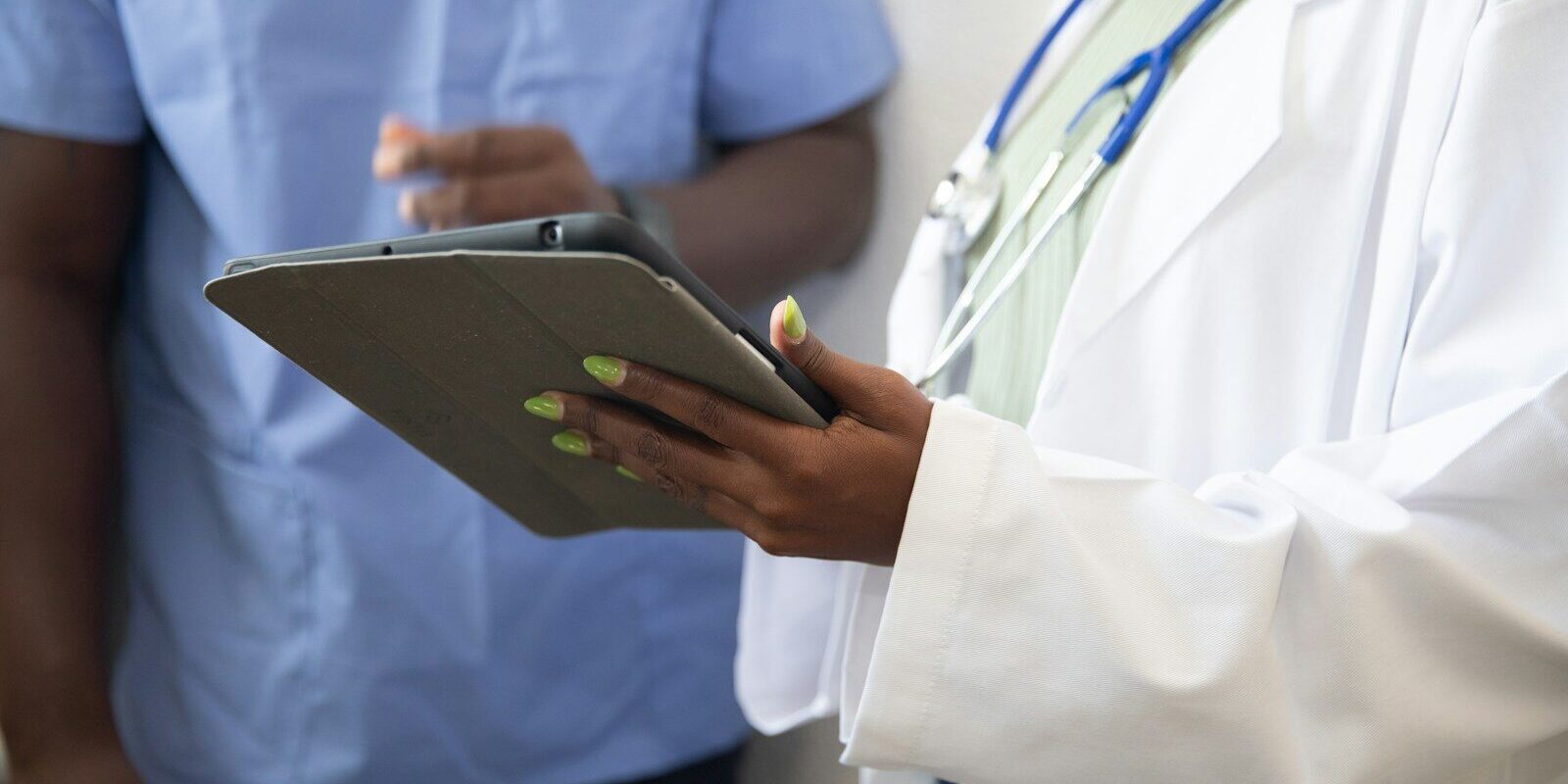 African healthcare worker reviewing facility compliance records on a tablet, representing quality and patient safety inspection