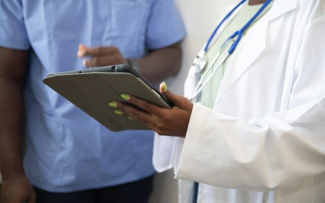 African healthcare worker reviewing facility compliance records on a tablet, representing quality and patient safety inspection
