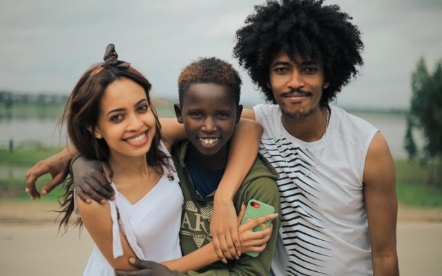 African family, parents and child, smiling together outdoors, representing a family relocating to Kenya for work under a Dependant's Pass