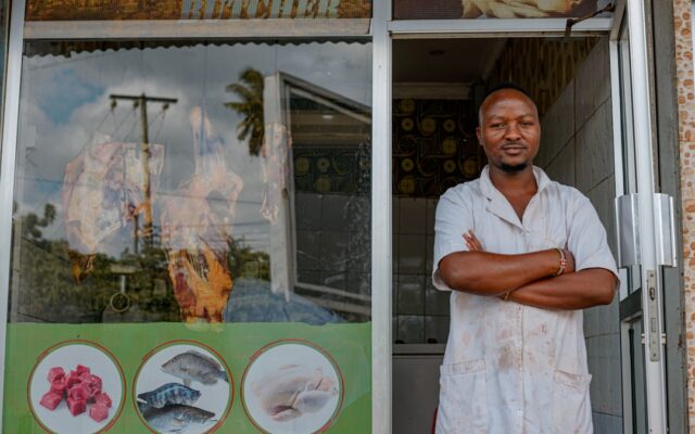 An African shopkeeper standing outside his store, representing a Kenyan franchise business