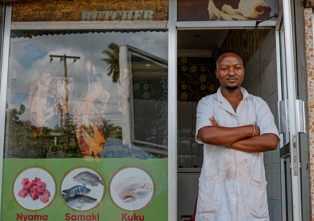 An African shopkeeper standing outside his store, representing a Kenyan franchise business