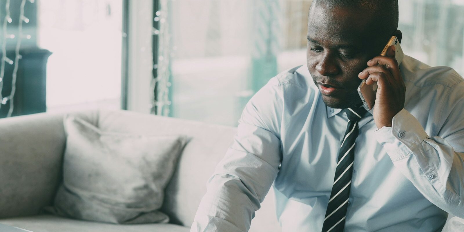 African businessman on the phone reviewing work permit paperwork and fees