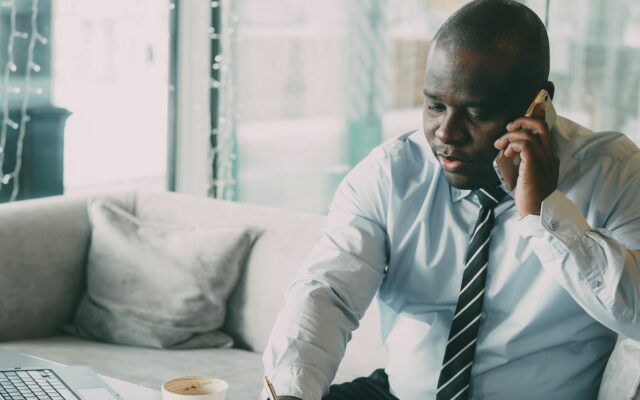 African businessman on the phone reviewing work permit paperwork and fees