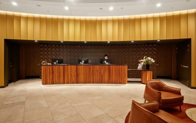Hotel management agreements: hotel reception lobby with a curved wooden front desk, representing a branded hotel run by a foreign operator