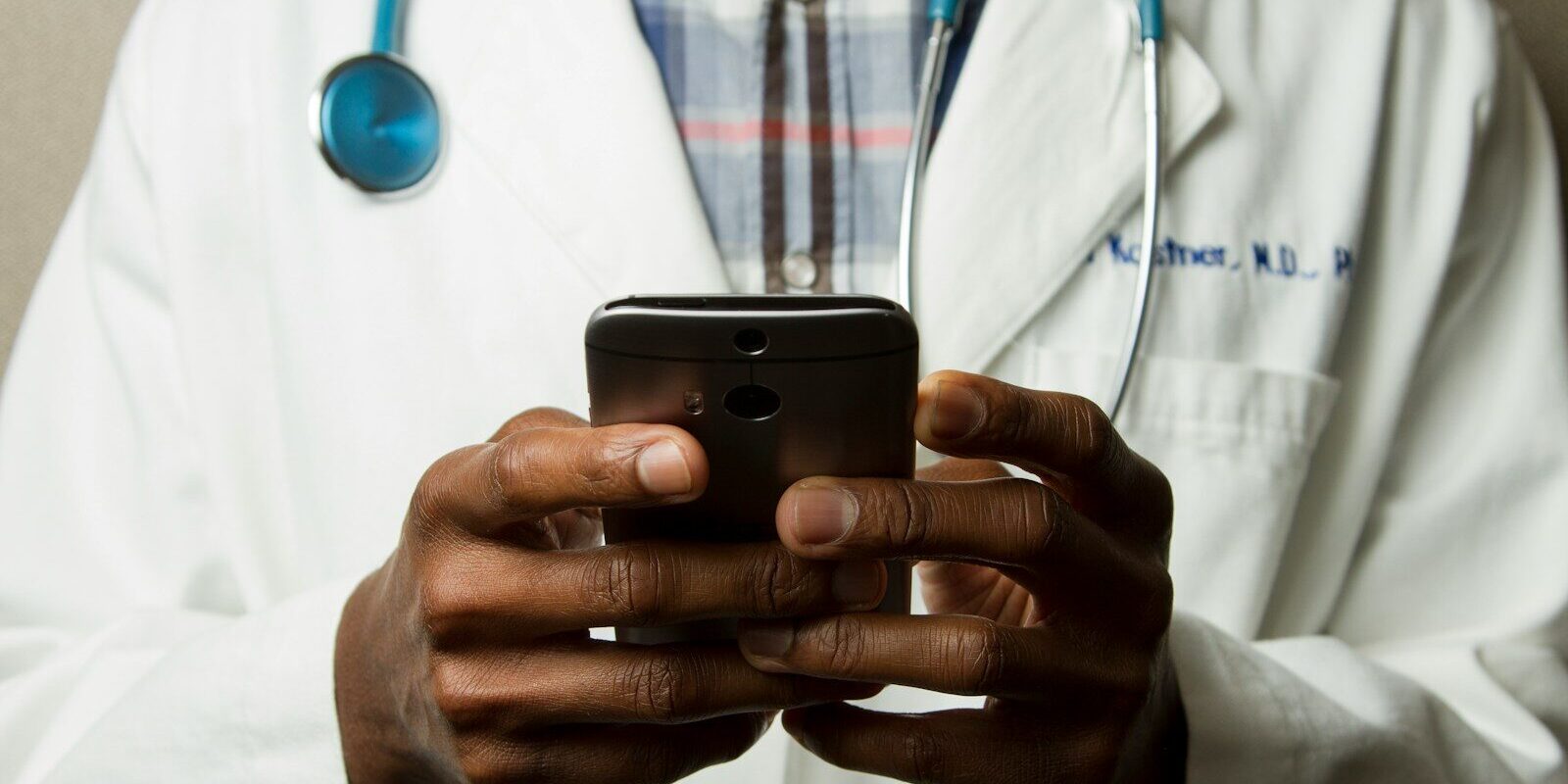 African doctor using a smartphone, representing remote monitoring and telehealth elements in decentralized clinical trials