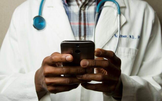 African doctor using a smartphone, representing remote monitoring and telehealth elements in decentralized clinical trials