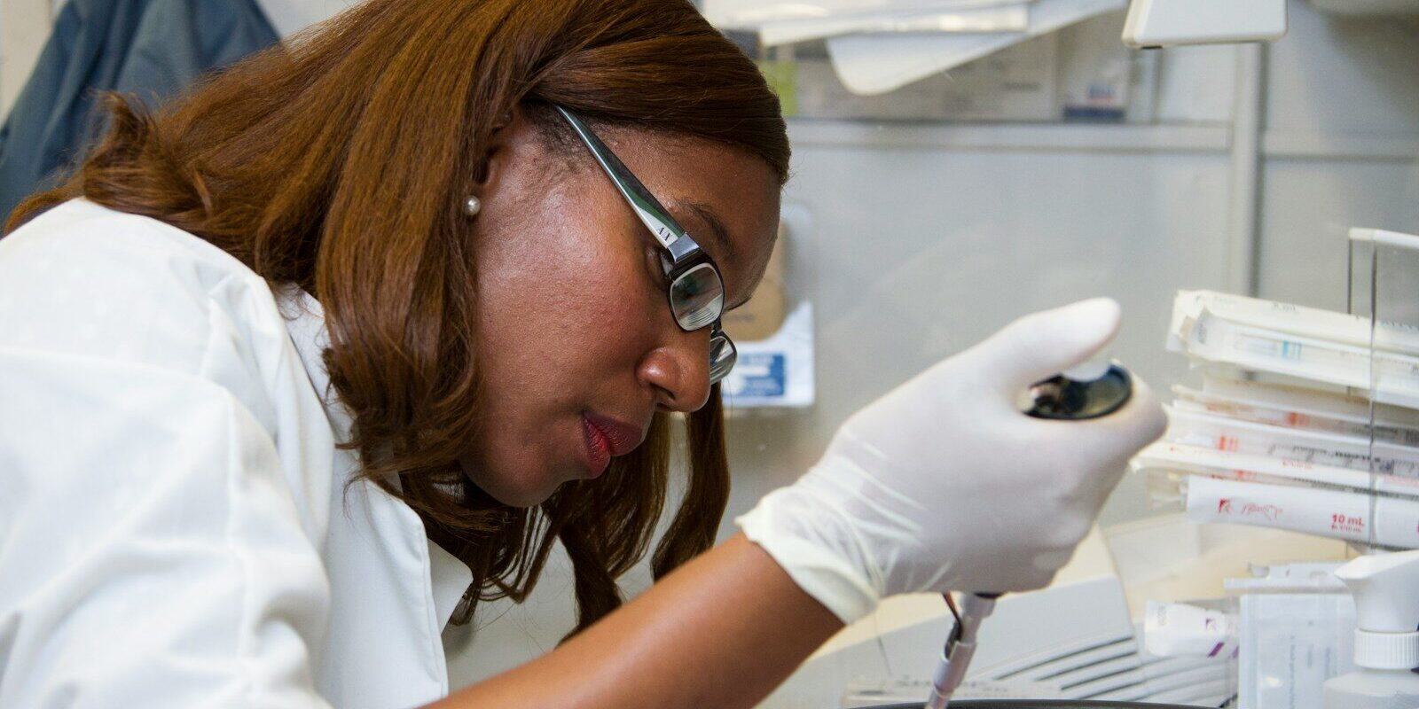 A scientist using a pipette to prepare a sample during mRNA vaccine technology transfer laboratory work