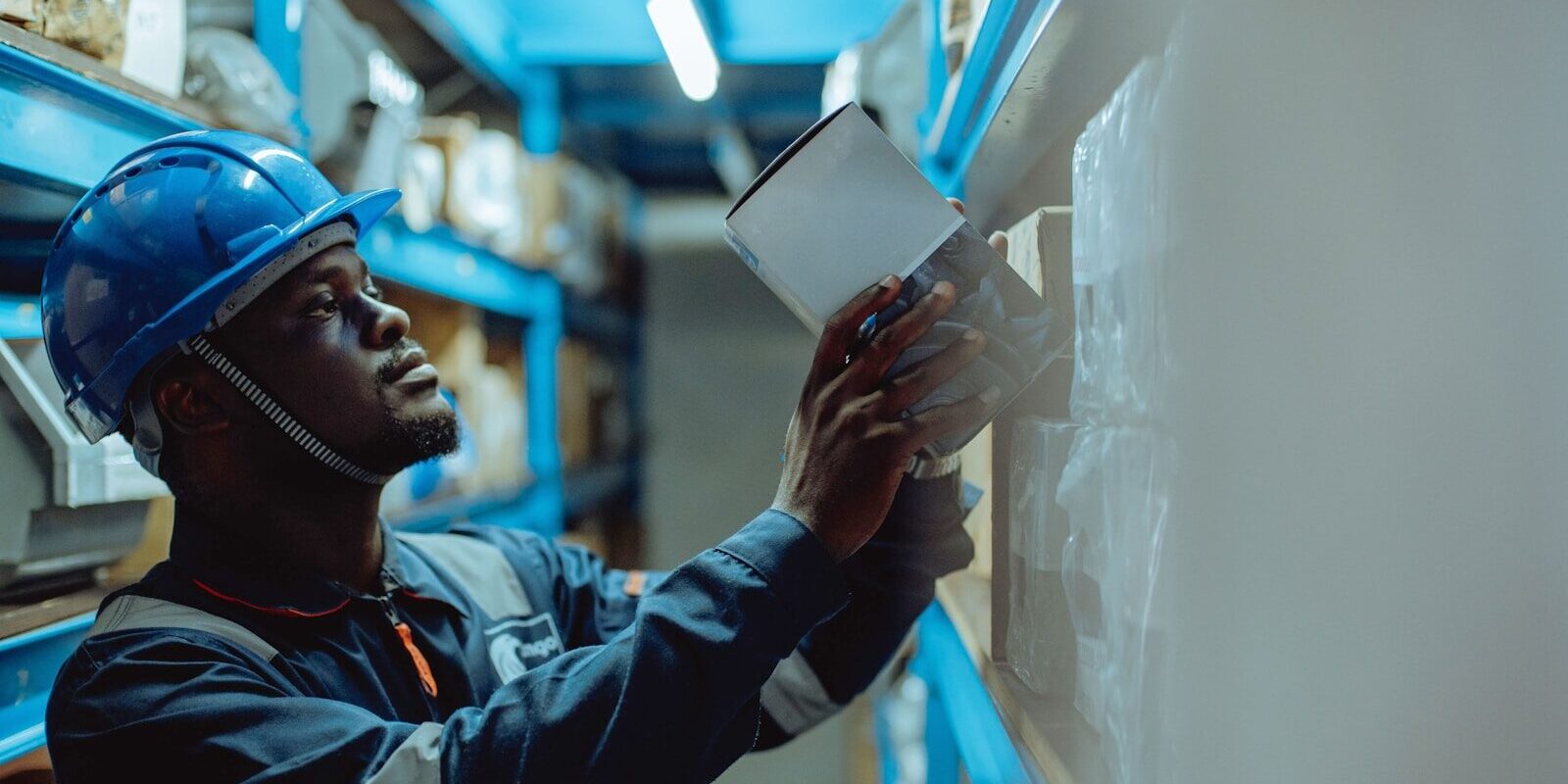 Medical Device Distribution Business Kenya — African warehouse worker in a hard hat checking inventory against a shipment