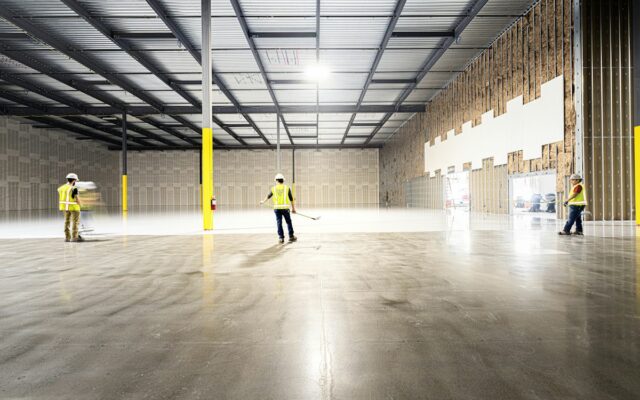 Construction workers walking through an empty industrial warehouse