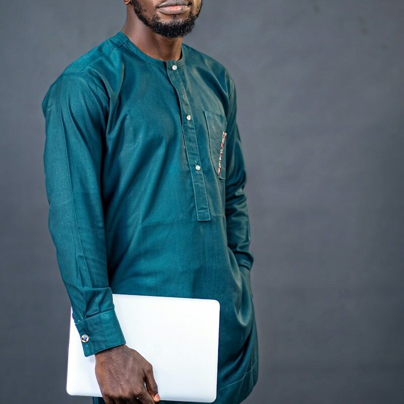 Parallel imports and exhaustion of rights: African businessman in a teal kaftan holding a laptop, representing a distributor or brand owner in Kenya