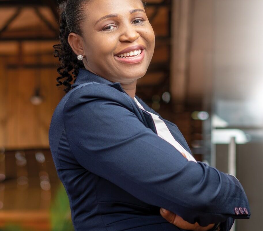 A confident African businesswoman in a blazer standing in an office, representing a life sciences investor