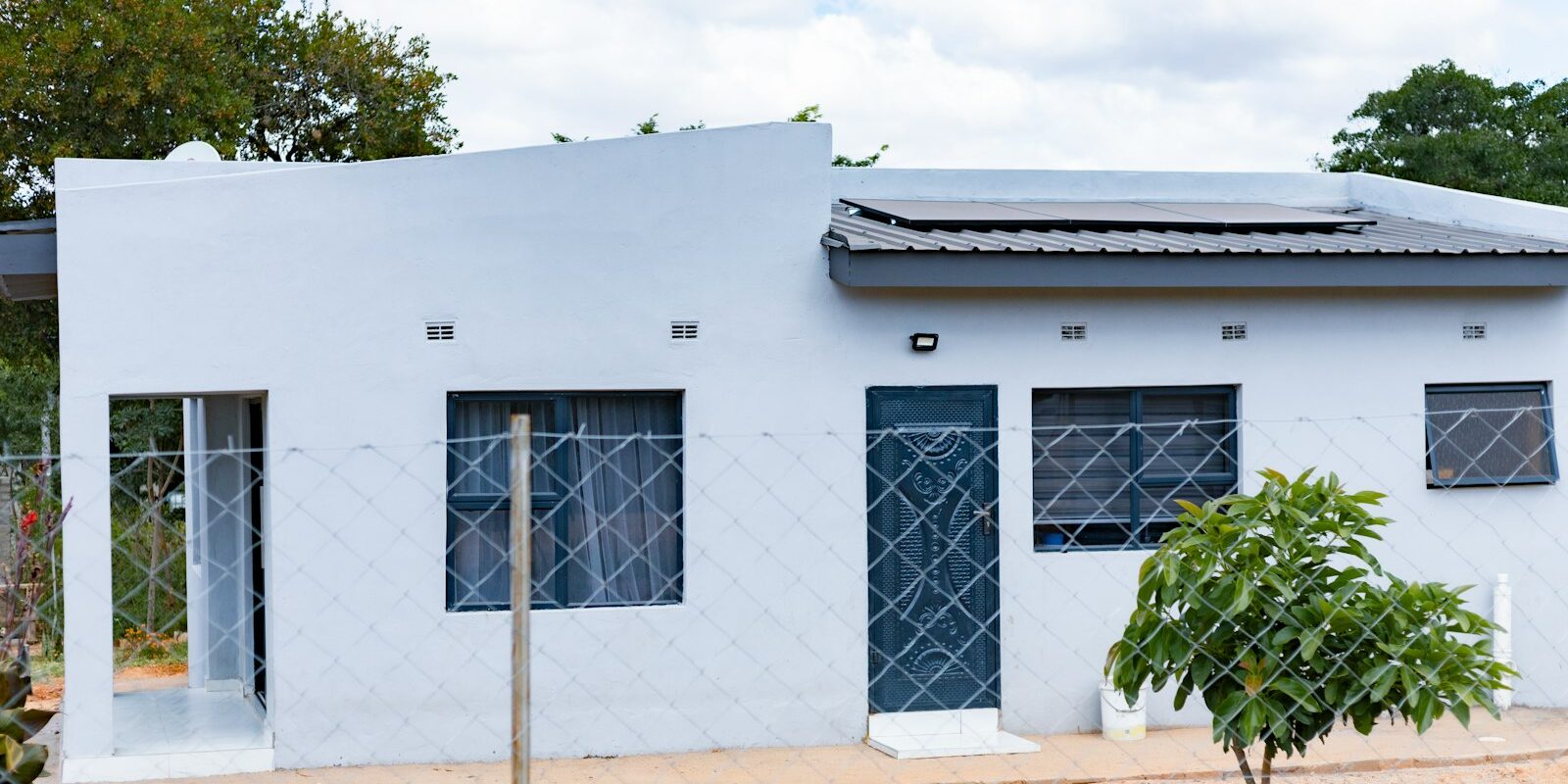 Small grey house with rooftop solar panels in a residential African neighbourhood
