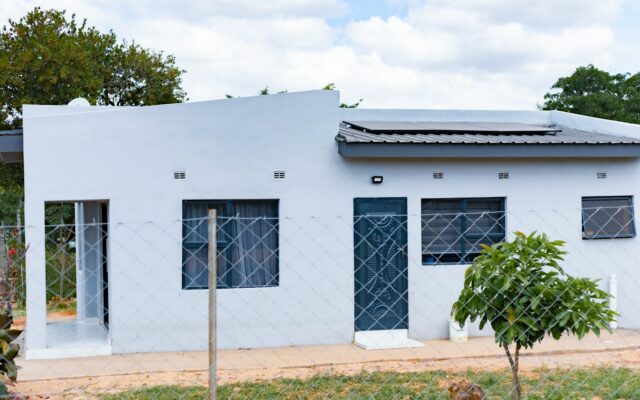 Small grey house with rooftop solar panels in a residential African neighbourhood