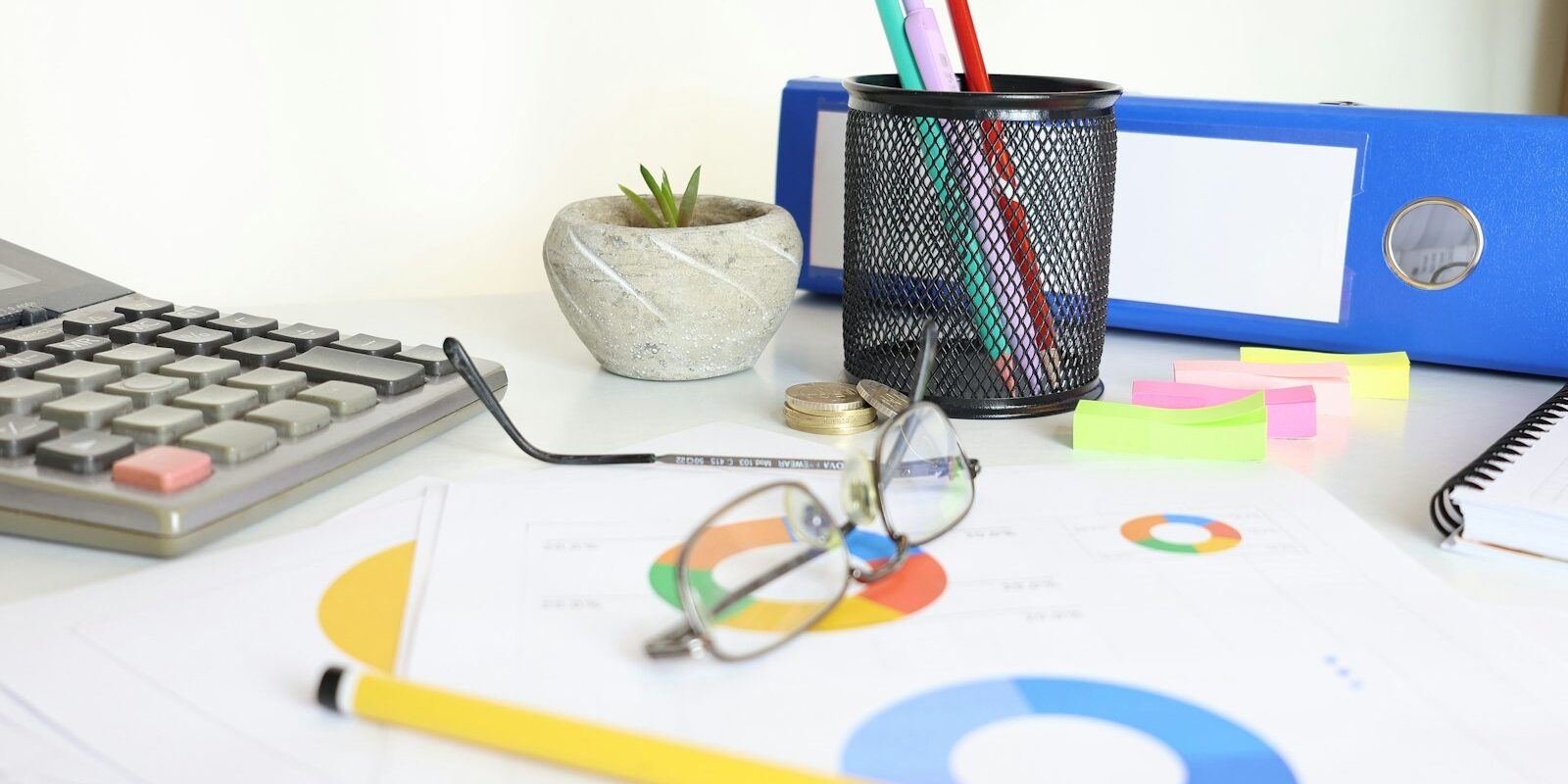 Desk with financial charts, a calculator and coins, representing profit calculations
