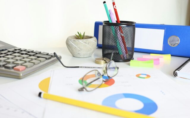Desk with financial charts, a calculator and coins, representing profit calculations