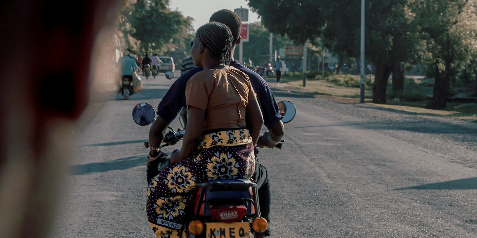 Motorcycle taxi carrying a passenger on a Kenyan road