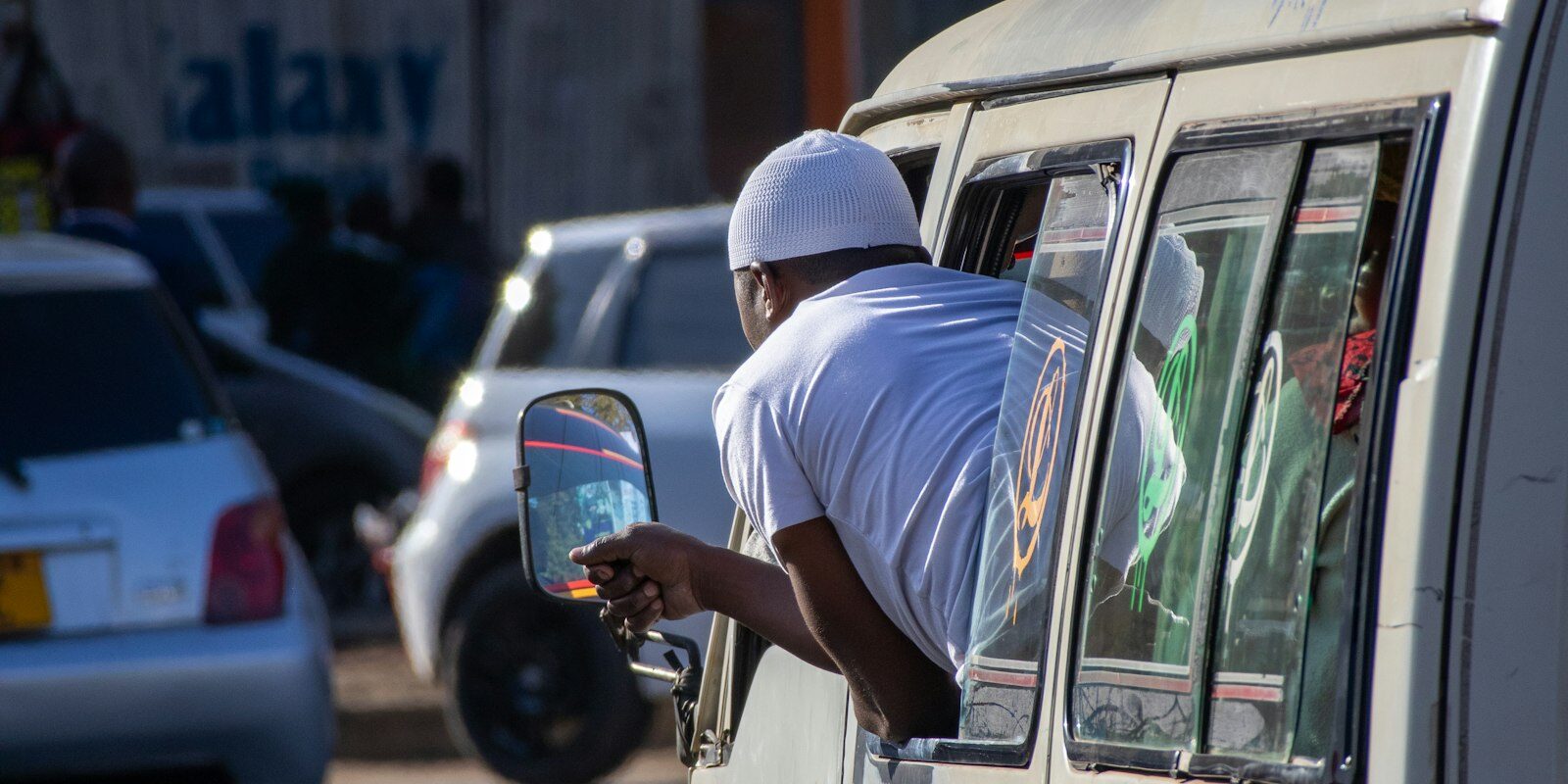 Public transport vehicle on a Nairobi street with a driver leaning out the window