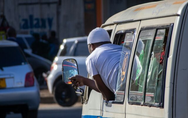 Public transport vehicle on a Nairobi street with a driver leaning out the window
