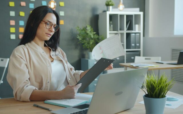 A business owner reviewing documents at her office desk