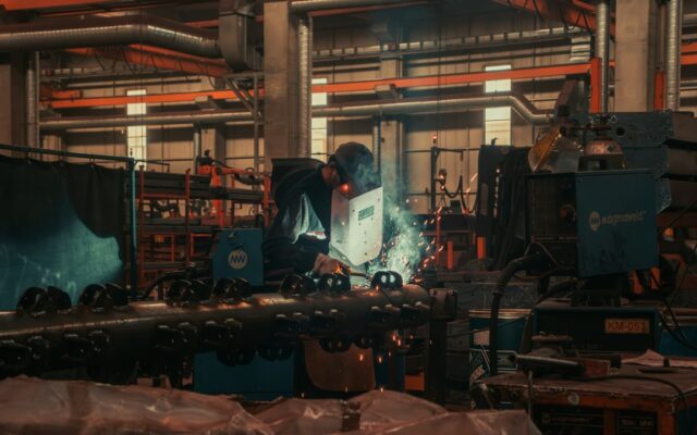 A worker welding metal components in a small manufacturing facility