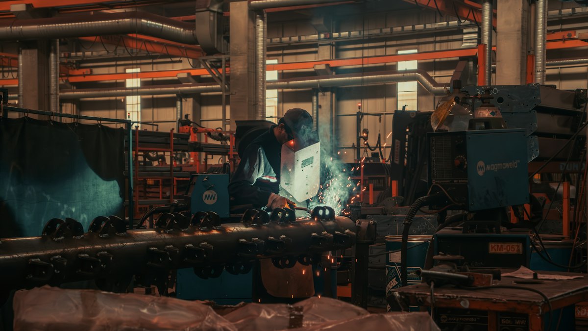 A worker welding metal components in a small manufacturing facility